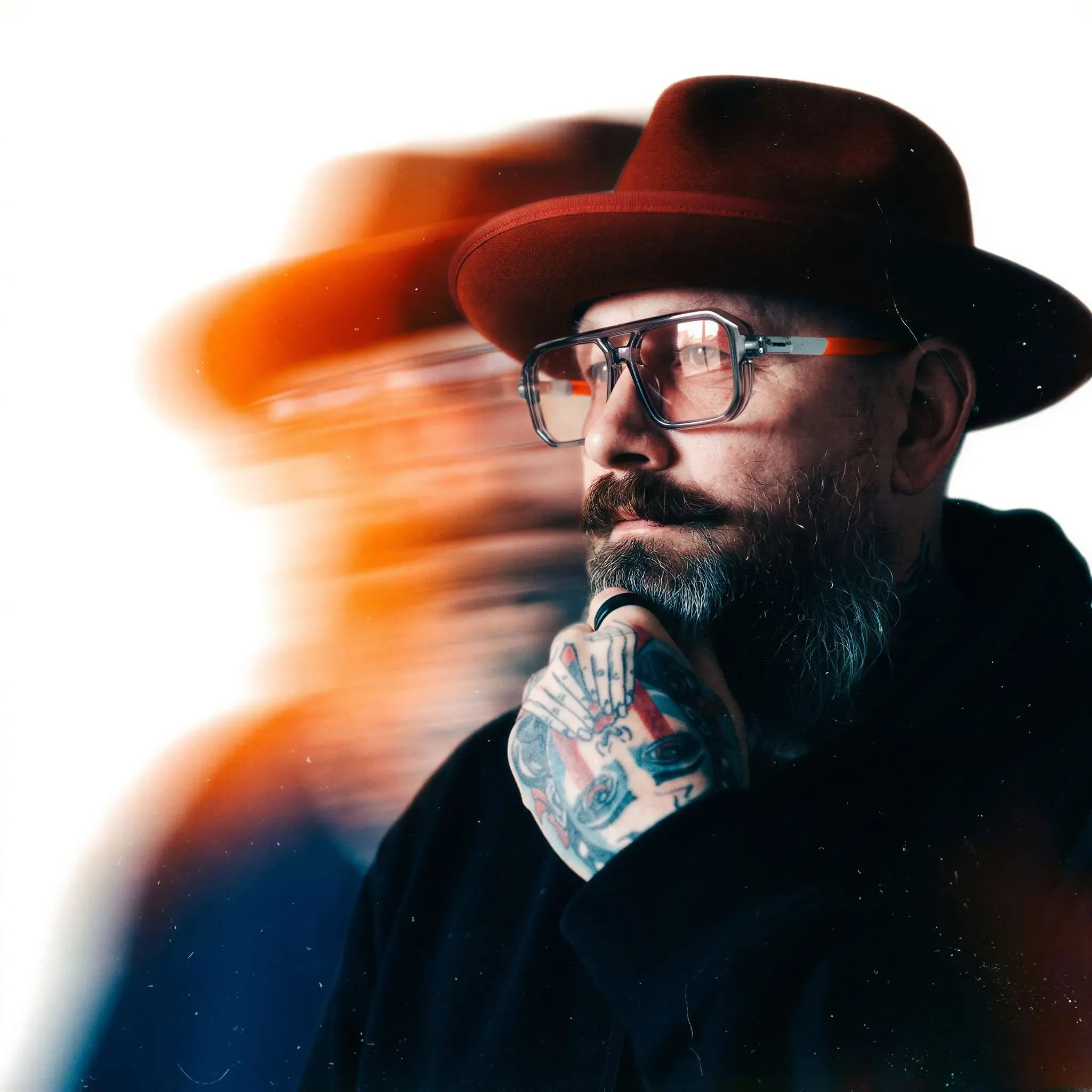 Rich Bennetts in a red fedora, hand at his chin, with a blurred double of himself beside him